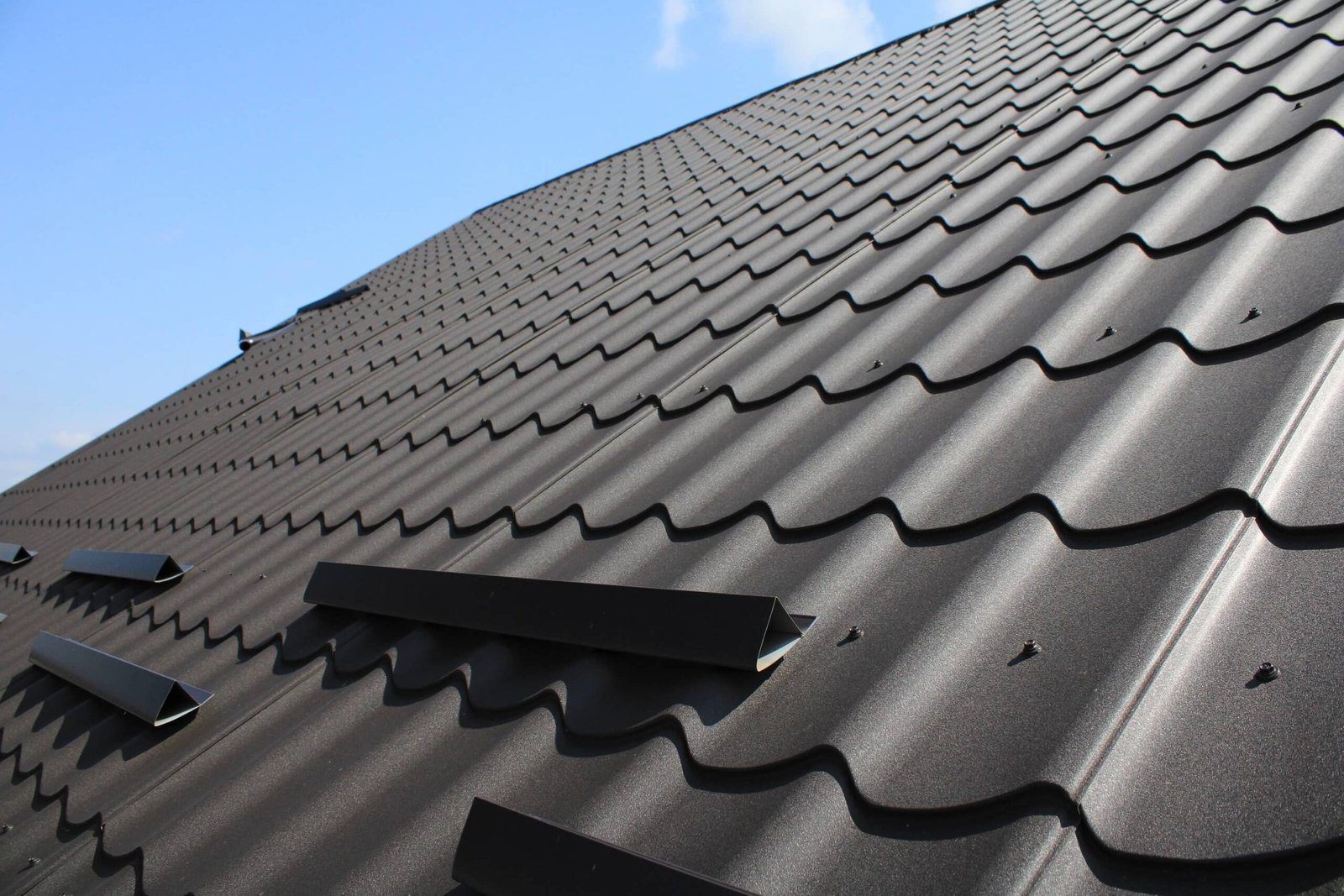 metal roof and blue sky background. Grainy texture of brown metal roof tiles.